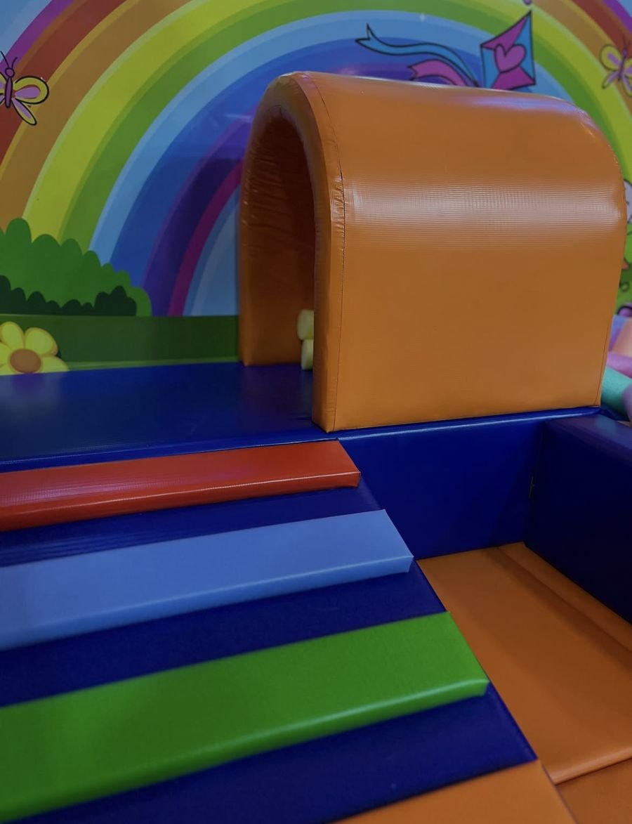 Circuito de espuma colorido com escadinha e túnel diante de um painel de arco-íris